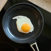 Svart non-stick stekpanna med stekt ägg