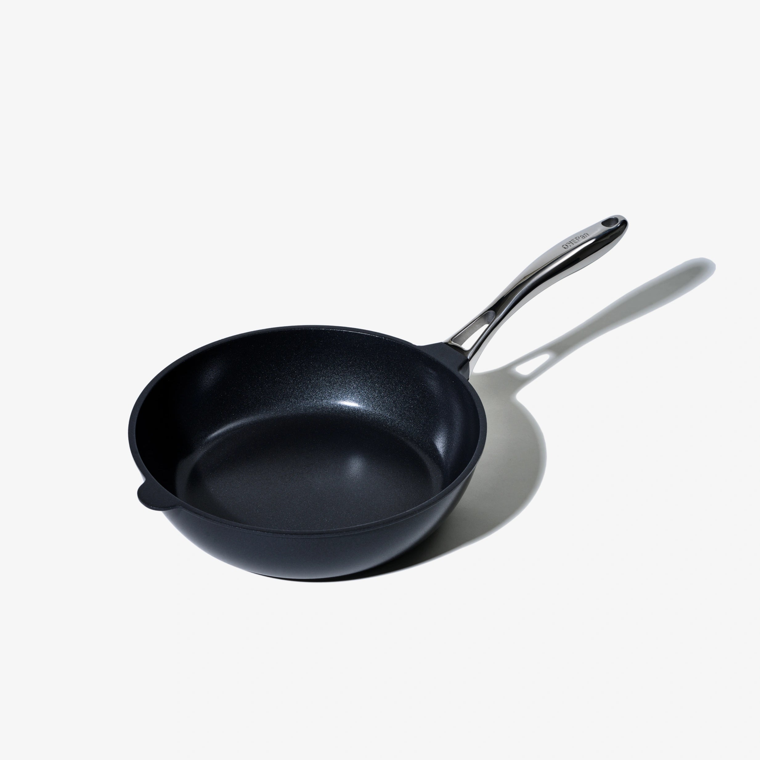 Svart stekpanna med avlångt handtag och rund botten.