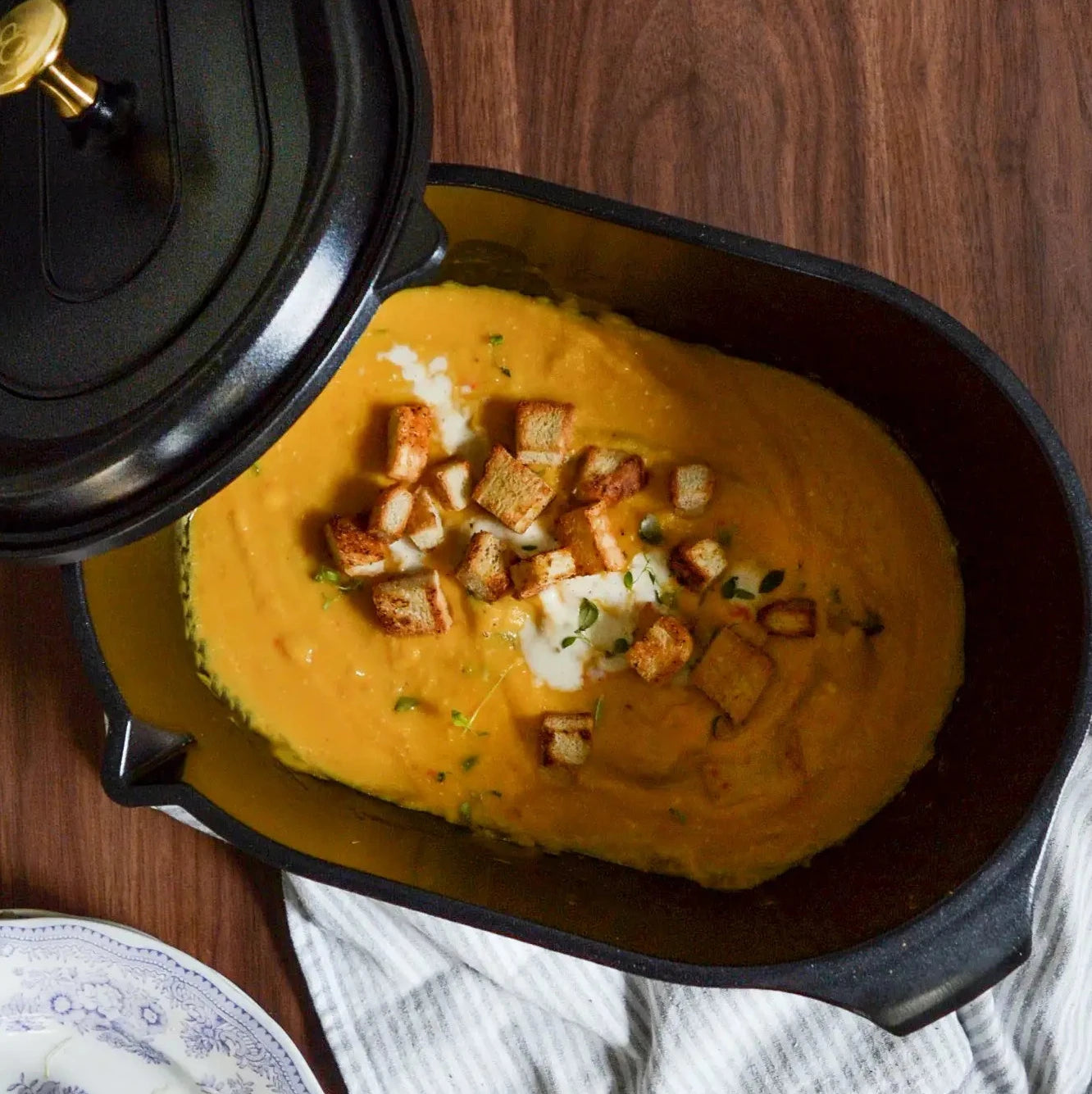 Svart gryta med lock, innehåll med gul soppa och krutonger, non-stick OnePot